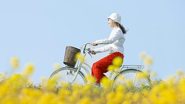 A young woman rides a bicycle through a summer field