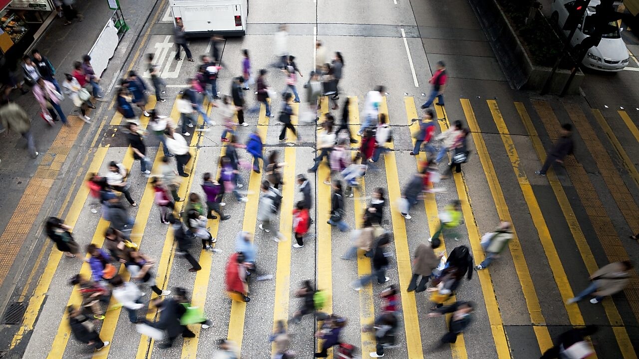 People cross a busy street in Hong Kong