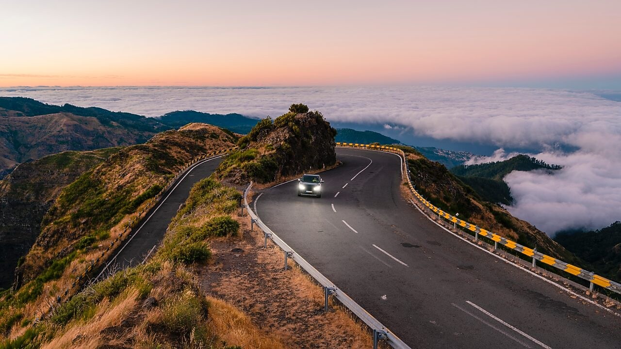 Car driving with headlights on a coastal route