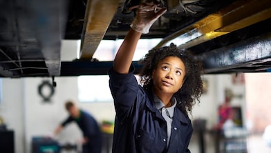 Service attendant standing over an car engine with an oil dip stick